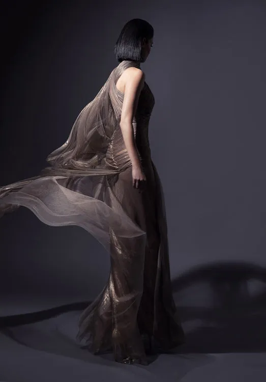 Exquisitely draped asymmetrical halter gown with caped open sleeve in fairy-spun bronze foiled silk tulle